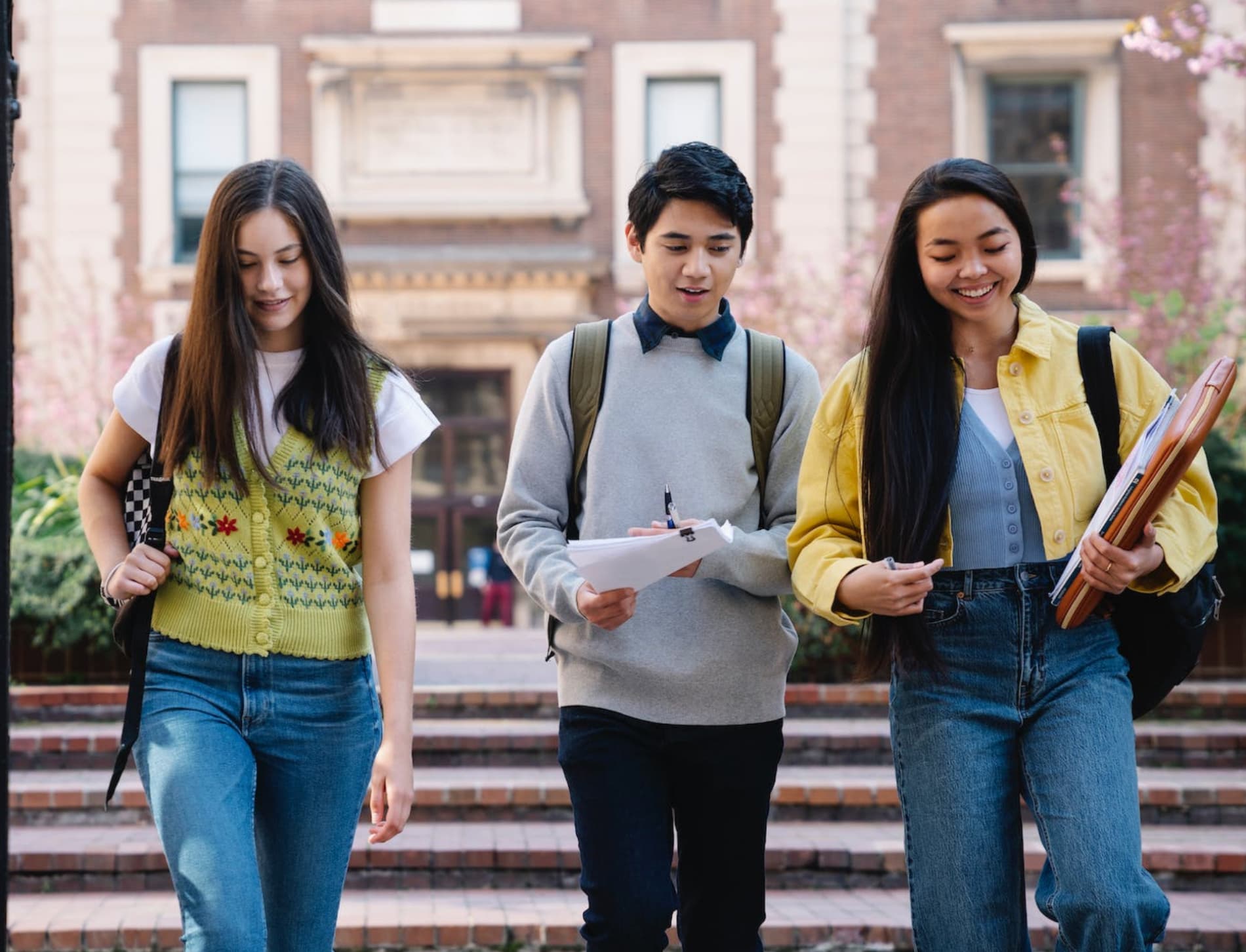 Three students with backpacks walking and talking on a school campus