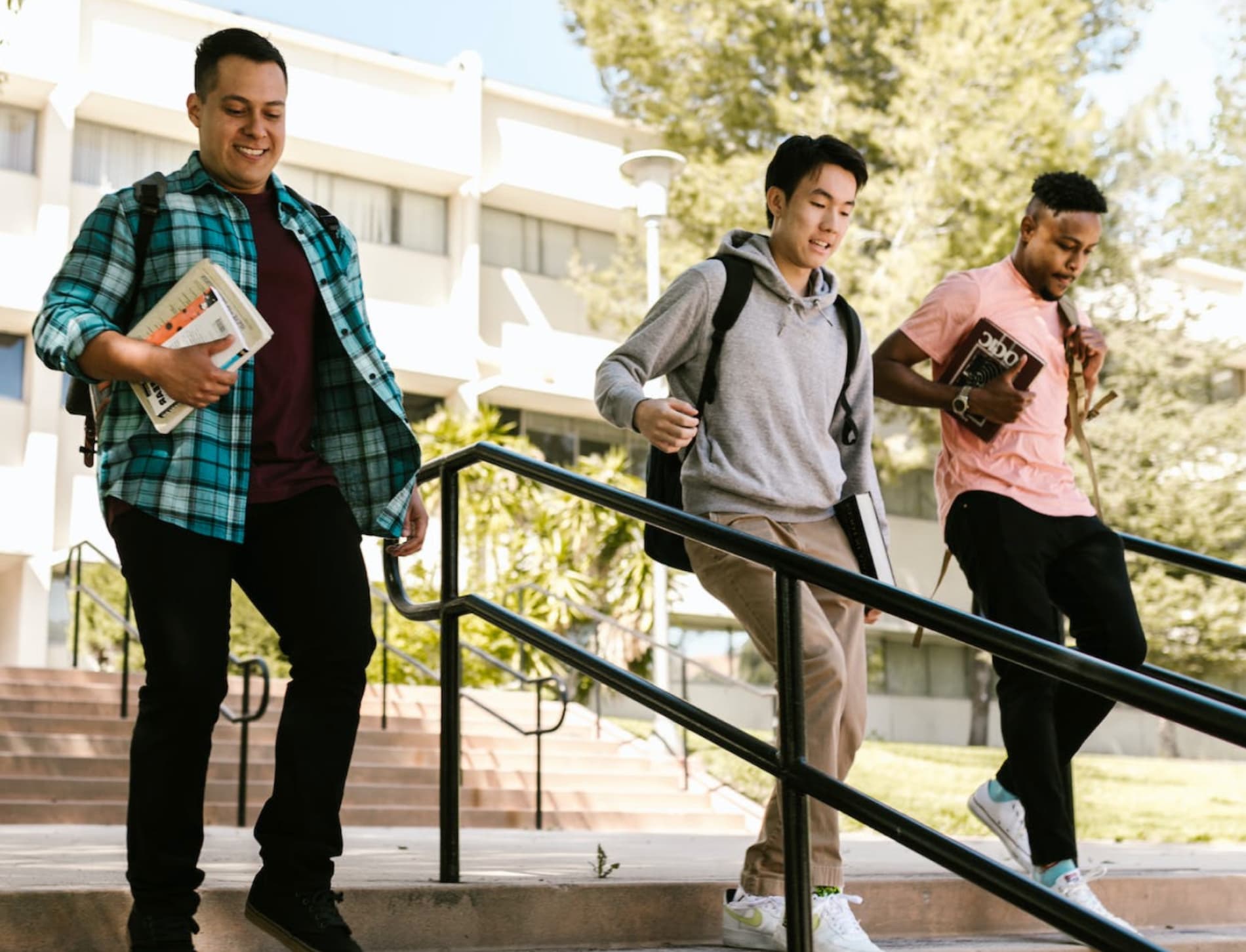 Three students carrying books and backpacks